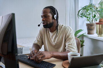 Multiracial man wearing headphones is browsing at his computer
