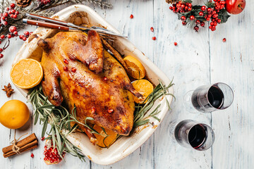 Roast Christmas duck with rosemary and oranges on rustic wooden table. Traditional roasted stuffed...