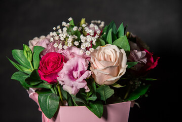 Beautiful bouquet of colorful rose flowers on a black background. Festive flowers concept with copy space. Flowers on a black background. Bouquet of fresh roses, freesias, eustoma and others.