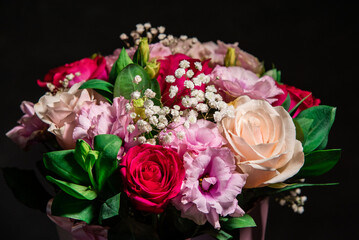 Beautiful bouquet of colorful rose flowers on a black background. Festive flowers concept with copy space. Flowers on a black background. Bouquet of fresh roses, freesias, eustoma and others.