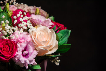 Beautiful bouquet of colorful rose flowers on a black background. Festive flowers concept with copy space. Flowers on a black background. Bouquet of fresh roses, freesias, eustoma and others.