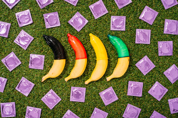 Bananas with multi colored condoms and packets on grass