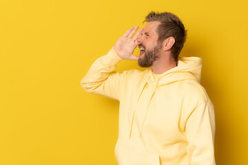 Young man over isolated yellow background shouting and screaming loud to side with hand on mouth. Communication concept.