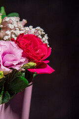 Beautiful bouquet of colorful rose flowers on a black background. Festive flowers concept with copy space. Flowers on a black background. Bouquet of fresh roses, freesias, eustoma and others.