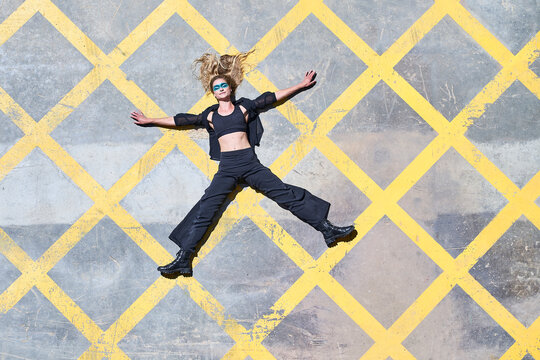 Carefree woman with arms outstretched lying down on footpath