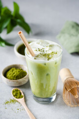 Obraz na płótnie Canvas Matcha ice latte in a glass on grey concrete table background. Healthy trendy vegan drink