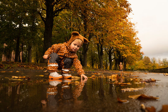 Boy playing at puddle in autumn park