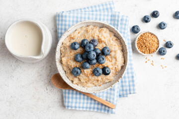 Fototapeta na wymiar Vegan oatmeal porridge with blueberries, flax seeds and soy milk