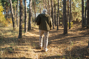 Senior male hiker walking with backpack in the wood while enjoying of the autumn nature