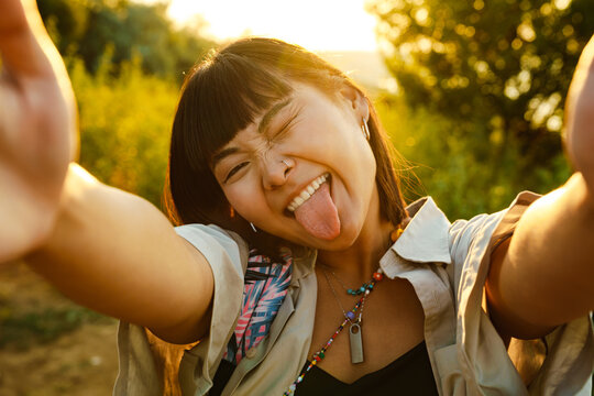 Asian young woman showing her tongue while taking selfie photo