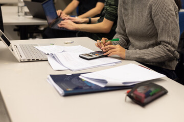 group young Asia lady student work on assignment, course work, worksheet, finance graph account chart using computer, calculator, phone market plan on desk in classroom or office