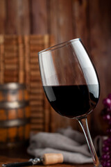 Slanted red wine glass with wine bottle on wooden still life background