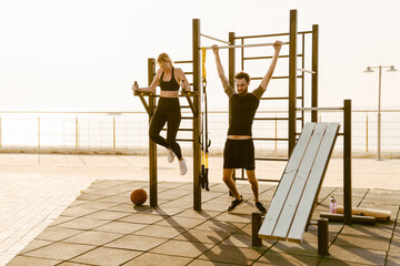 Young man and woman working out together on sports ground