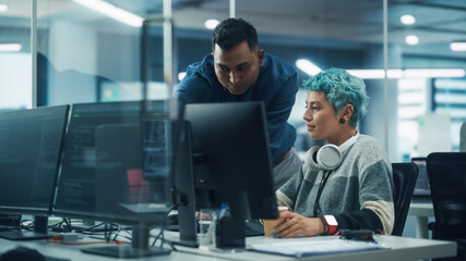 Teamwork In Diverse Office: Project Manager Talks with Creative Solutions Specialist, They Discuss Design Shown Desktop Computer. Professionals Create Modern Content, e-Commerce Social Media Strategy