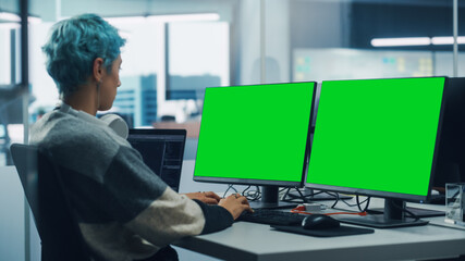 In Diverse Office: Female Programmer is Working on Green Screen Computer, Chroma key and Coding Language User Interface. Digital Entrepreneur Creating Software, e-Commerce App Design. Over Shoulder