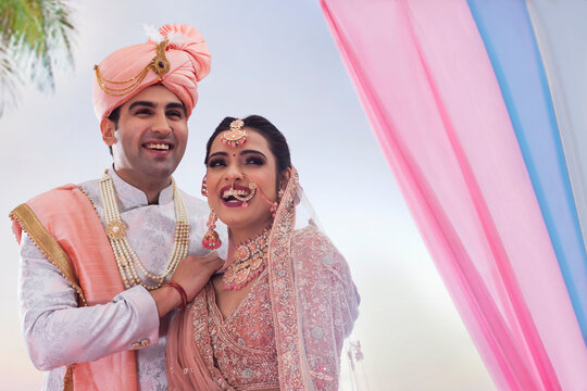 Indian bride and groom in traditional wedding dress smiling together