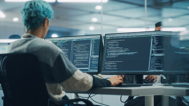 In Diverse Office: Female Programmer is Working on Desktop Computer, Screen Shows Coding Language User Interface. Digital Entrepreneur Creating Modern Software, e-Commerce App Design. Over Shoulder