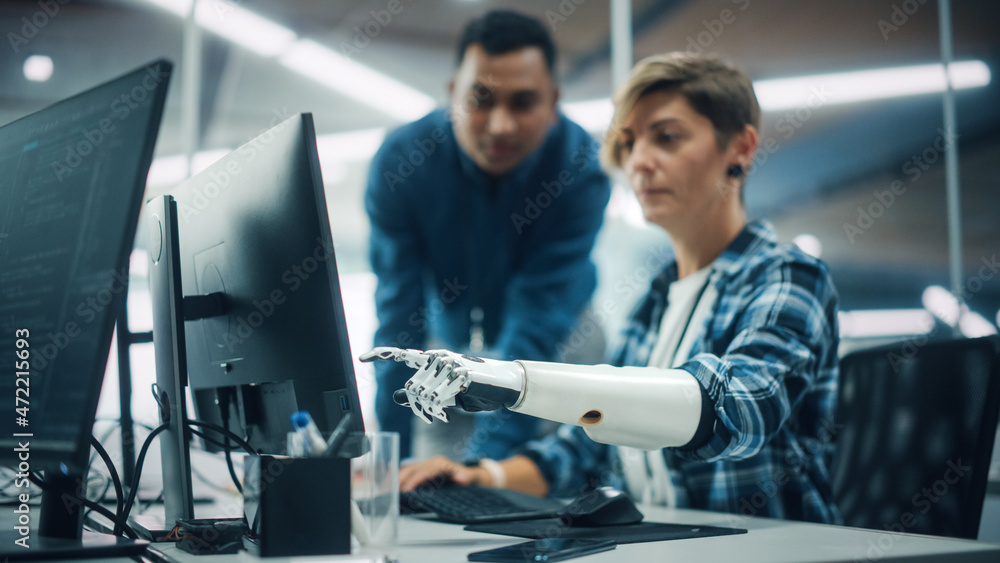 Poster Teamwork In Diverse Office: Smiling Project Manager Talks with Happy Woman with Disability with Prosthetic Arm to Work on Desktop Computer. Professionals Create e-Commerce Software App Solution