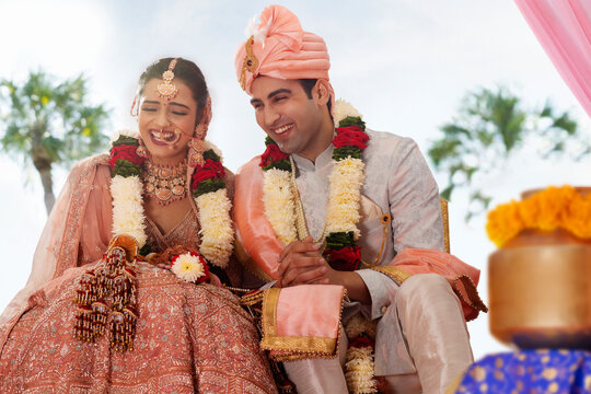 Happy bride and groom sitting together at wedding mandap