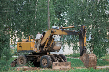 the excavator driver climbs into the cab