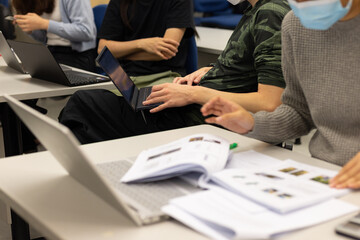 group young Asia lady student work on assignment, course work, worksheet, finance graph account chart using computer, calculator, phone market plan on desk in classroom or office