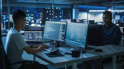 Night Office: Young Japanese Man in Working on Desktop Computer. Diverse Multi-Ethnic Team of Programmers Typing Code, Creating Modern Software, e-Commerce App Design, e-Business Programming.