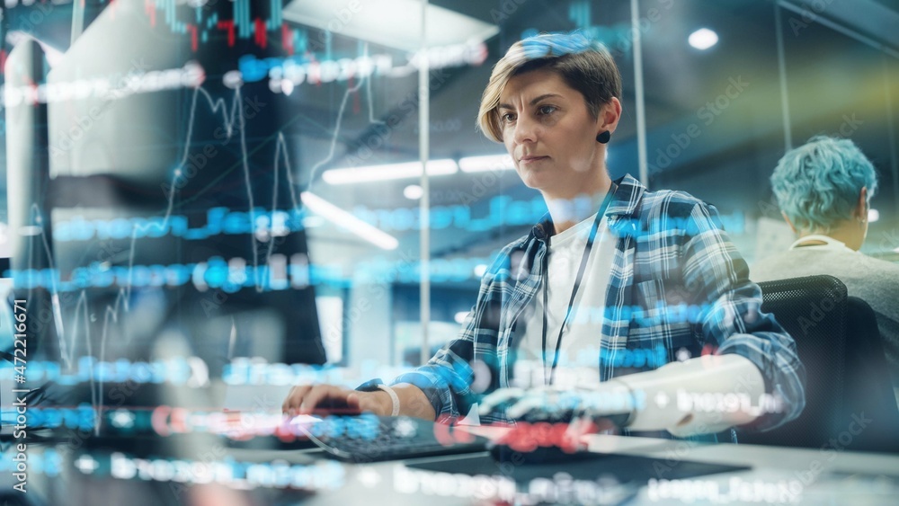 Poster Shot with Visualisation of Running Computer Code on Foreground. Portrait of Motivated Woman with Disability Using Prosthetic Arm to Work on Computer in Body Positive Office. Myoelectric Bionic Hand