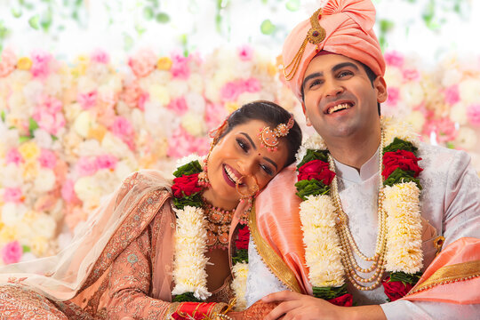 Portrait of a happy Indian wedding couple sitting together on mandap