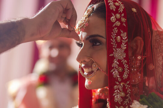 Indian groom putting sindoor on brides forehead during wedding ceremony