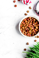 dry dog food in bowl on stone background top view
