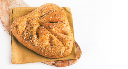 Rustic fougasse bread with herbs and sea salt, placed on a wooden board with a yellow napkin against a white background