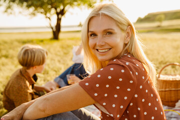 White woman smiling during picnic with her family on field