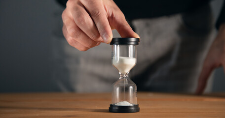Businessman holding hourglass on table