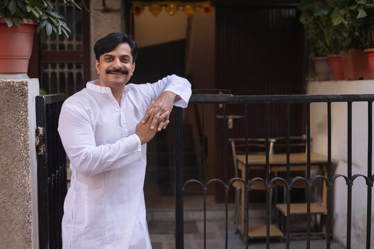 Middle age man in white kurta standing at entrance gate in the morning