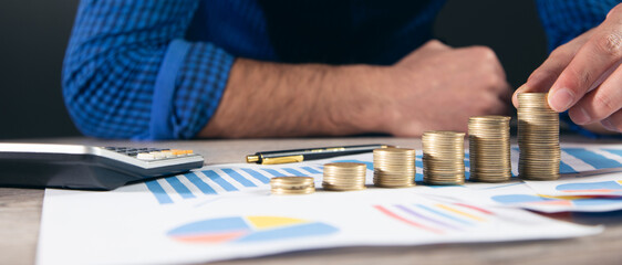Man stacking coins with calculator