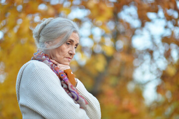 Portrait of sad senior woman in autumn park