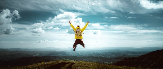 Man traveler on mountain summit enjoying nature view with hands raised over clouds - Sport, travel...