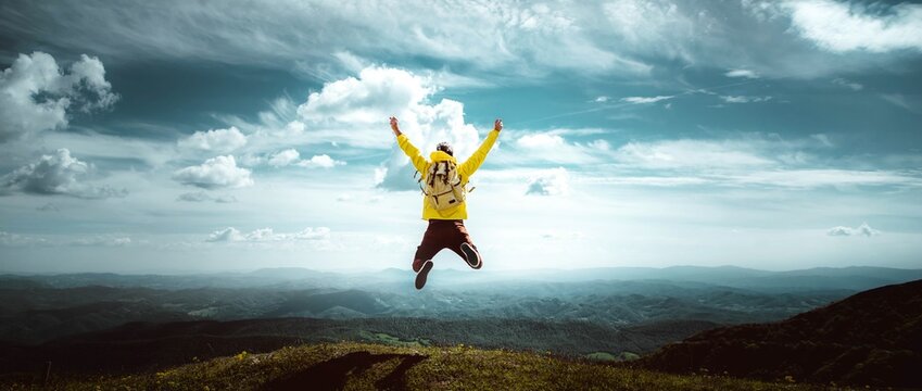 Man traveler on mountain summit enjoying nature view with hands raised over clouds - Sport, travel business and success, leadership and achievement concept