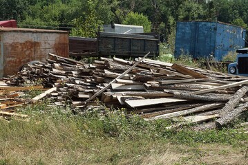 a pile of firewood from long wooden planks and logs on the street 