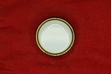 one large white plastic button on red clothing fabric