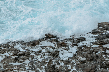 Dangerous splashing strong waves after storm. Wild rocky seashore, windy weather. Abstract blue sea water with white wave for background. Crashing ocean waves. Power of water