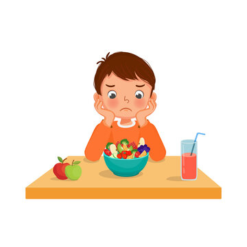 Little boy picky eater feeling unhappy looking at bowl of fruits and vegetables with hands on the cheek.

