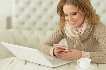 Smiling young woman with laptop and smartphone