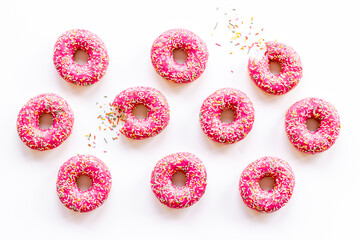 Fototapeta na wymiar Pink frosted donuts with colorful sprinkles. Bakery background