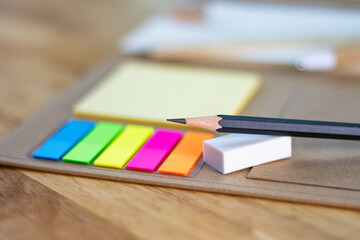 selective focus pencil for writing and multicolored square colorful sticky notes, rulers, and paper book on wood table concept equipment office and school