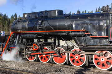 Naklejka premium Russia, Karelia, Ruskeala, 08.09.2021. A steam locomotive in the Ruskeala Mountain Park and smoke from the chimney. The concept of recreation in Karelia. editorial use only.