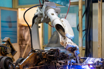 Automation concept: Selective focus on welding head of robot in automotive part manufacturing plant.
