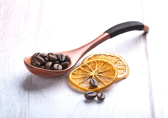 Coffee beans in a wooden spoon on a light wooden background