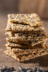 Stack of biscuit crackers with sunflowers seeds and sesame, vertical, selective focus