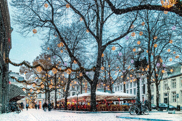 Bars and restaurants with snow and christmas lights on the Onze Lieve Vrouweplein square in...